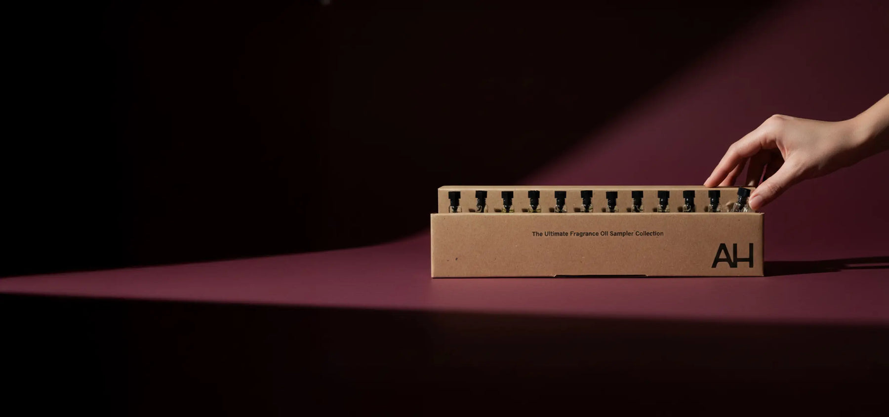 Hand opening a cardboard box with 'AH' branding on a dark background